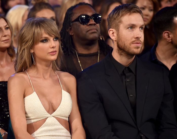 Taylor Swift and Travis Kelce sitting side by side at a formal event, body language expert observing their interaction. Taylor Swift and Travis Kelce sitting side by side at a formal event, body language expert observing their interaction.