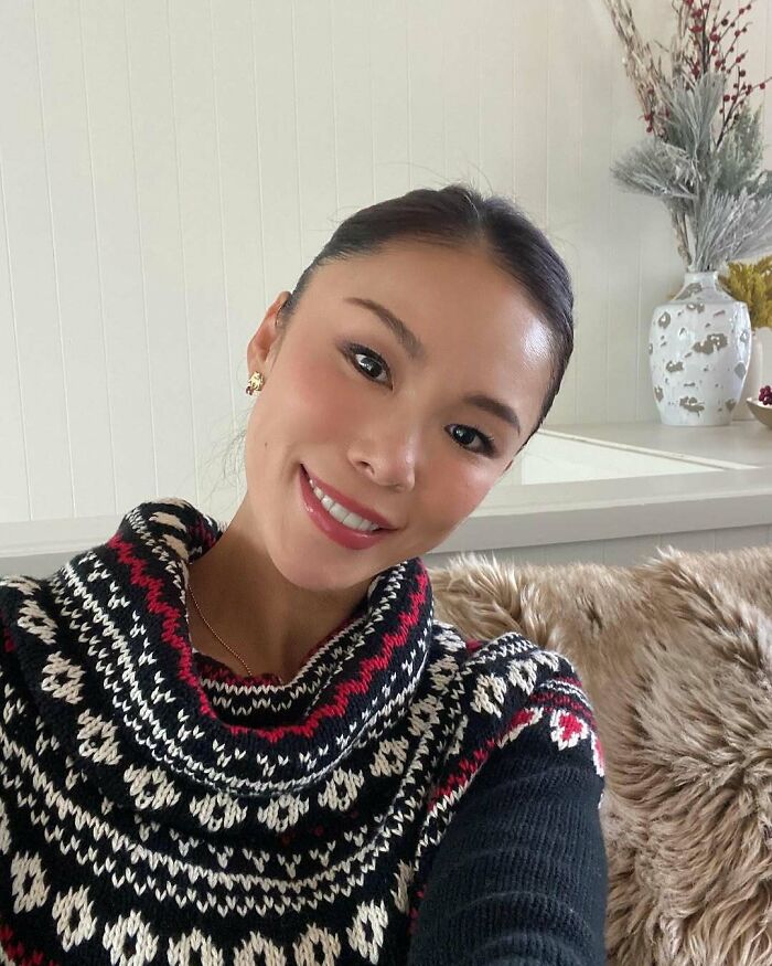 Miss Universe winner smiling in a cozy black and white patterned sweater, captured in a stunning indoor photo.