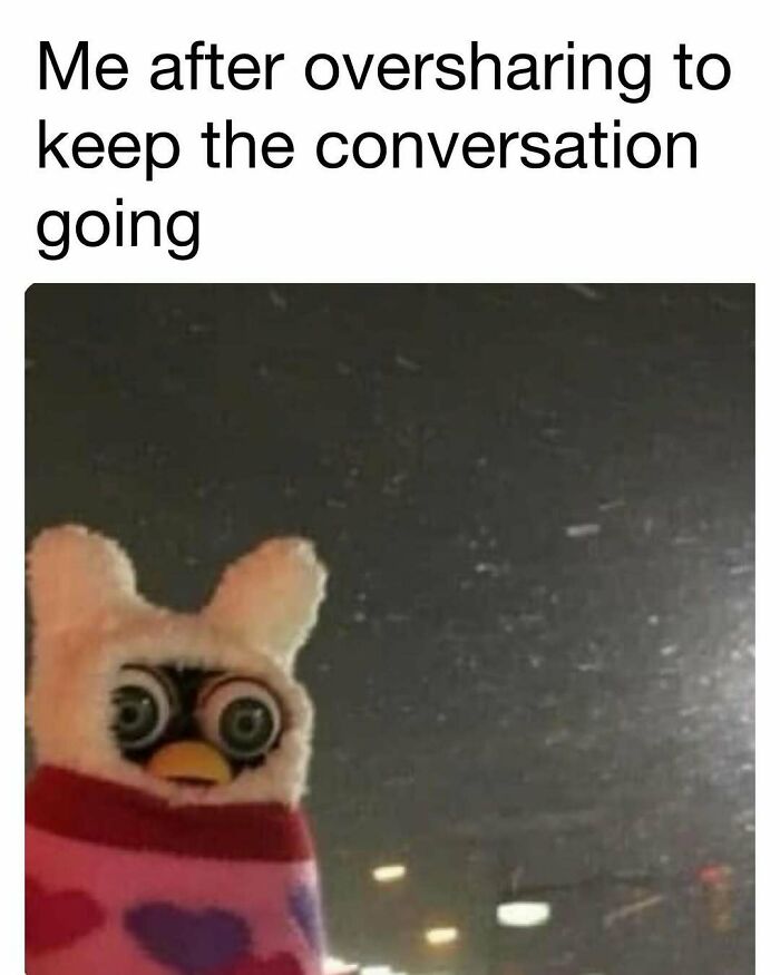 Furby doll wrapped in a blanket with wide eyes, captioned about oversharing to keep the conversation going, funny meme.