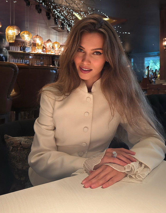 Former Miss Universe contestant, 30, sitting at a table in a cozy restaurant with soft lighting and festive decor. Former Miss Universe contestant, 30, sitting at a table in a cozy restaurant with soft lighting and festive decor.
