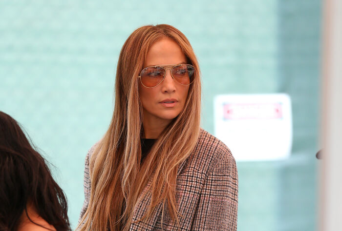 Jennifer Lopez wearing sunglasses and a plaid jacket, in a public setting related to Chanel brand controversy. Jennifer Lopez wearing sunglasses and a plaid jacket, in a public setting related to Chanel brand controversy.