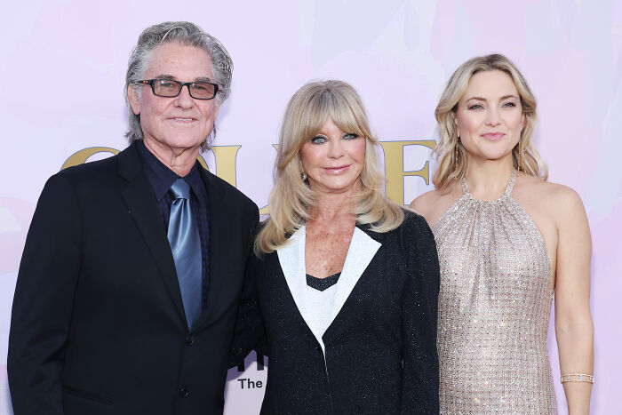 Three generations of a legendary entertainment family posing at a red carpet event, dressed in formal attire.