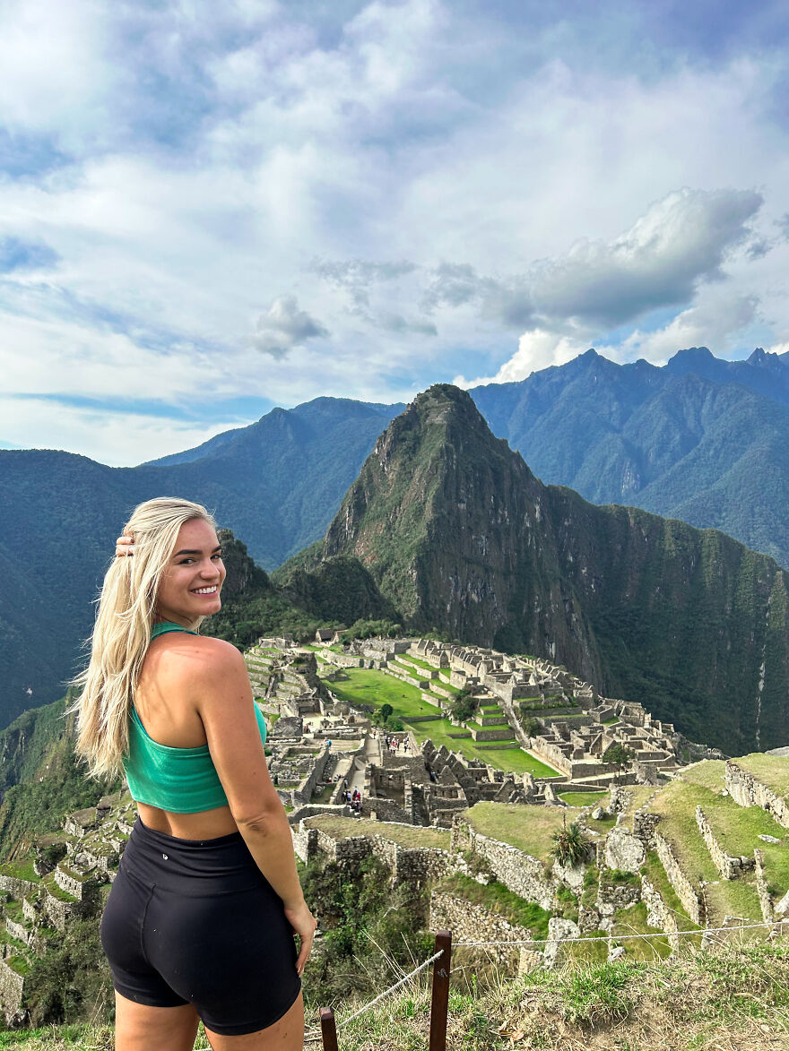 Young woman smiling at Machu Picchu with mountains in background, representing a one-way flight to Australia and debt transformation.
