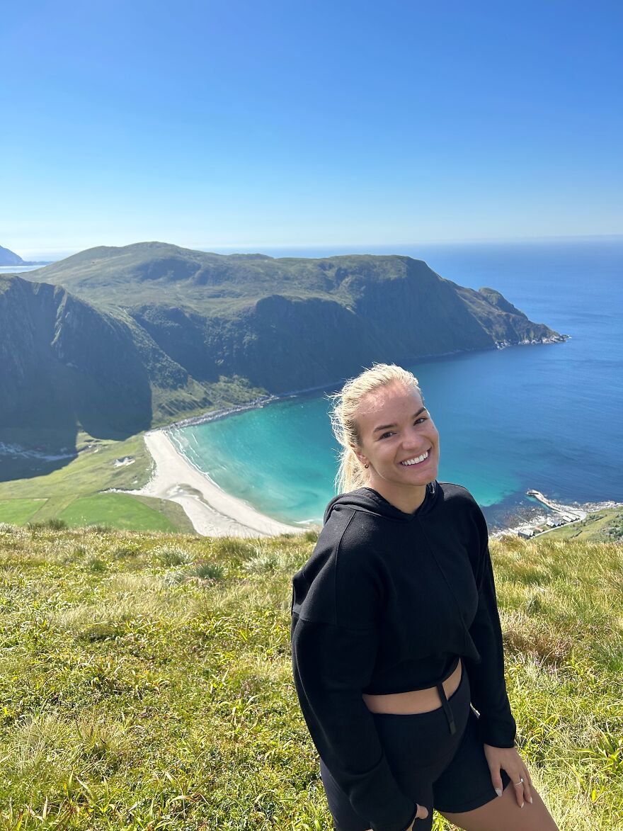 Smiling woman in black outfit standing on grassy hill with ocean and cliffs in background, capturing debt payoff journey to Australia. Smiling woman in black outfit standing on grassy hill with ocean and cliffs in background, capturing debt payoff journey to Australia.