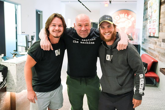 Dana White smiling with two men in casual clothing, highlighting UFC and Dana White's net worth growth. Dana White smiling with two men in casual clothing, highlighting UFC and Dana White's net worth growth.