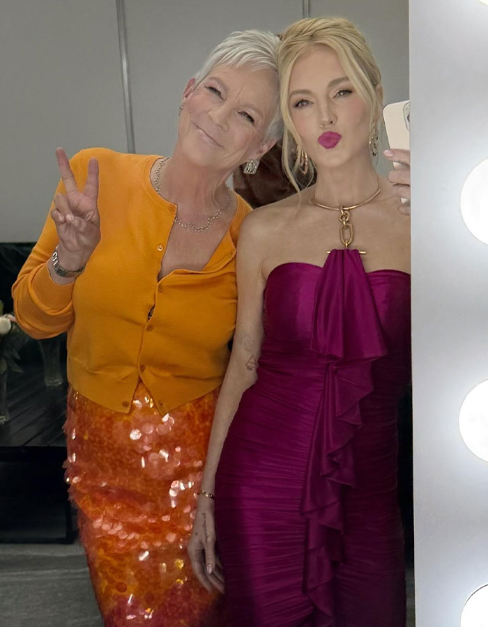 Jamie Lee Curtis posing with a friend, wearing an orange outfit, responding to fan memes about her viral cleavage moment. Jamie Lee Curtis posing with a friend, wearing an orange outfit, responding to fan memes about her viral cleavage moment.