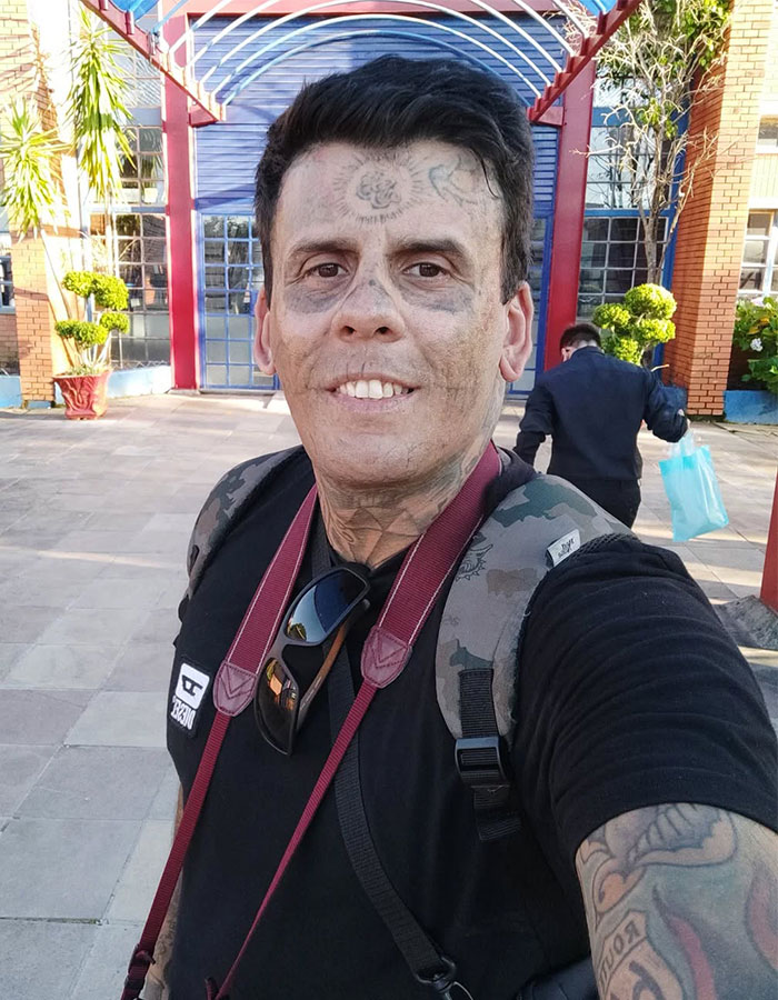 95% tattooed Brazilian Steve-O man showing his dramatic new look after tattoo removal outdoors with backpack and camera. 95% tattooed Brazilian Steve-O man showing his dramatic new look after tattoo removal outdoors with backpack and camera.