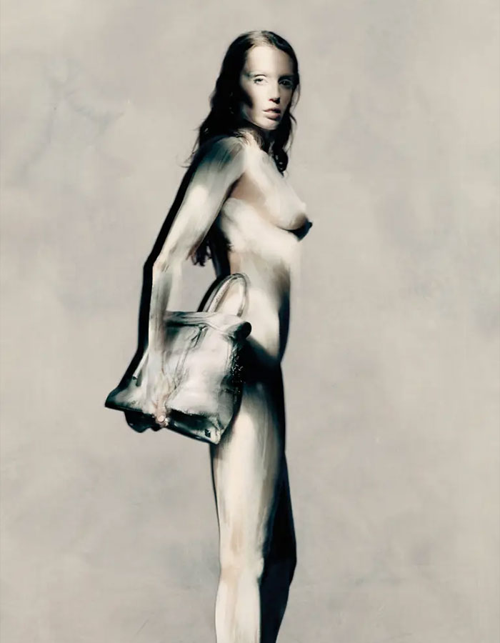 A model with striking body paint holding a handbag in a Maison Margiela campaign, showcasing bold fashion artistry. A model with striking body paint holding a handbag in a Maison Margiela campaign, showcasing bold fashion artistry.