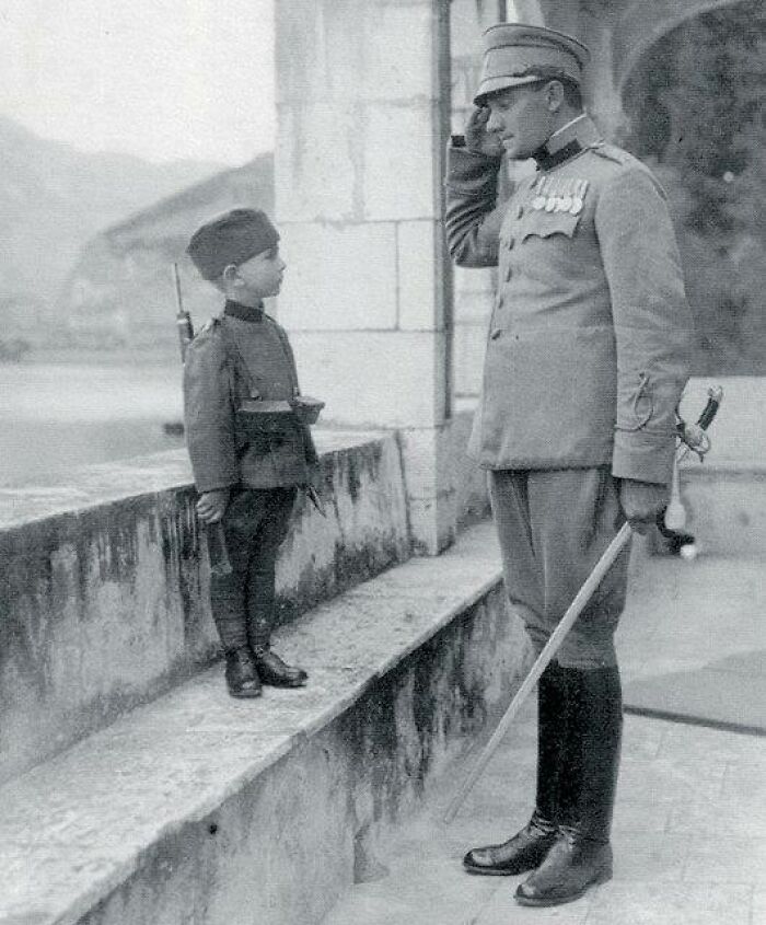 Young soldier saluting an officer in uniform, showcasing daily life beyond the WWI trenches in a historic black and white photo.