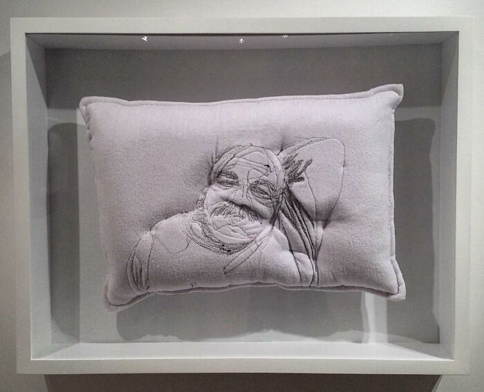 Embroidered pillow with a detailed portrait capturing the beauty of sleep in a minimalist display frame.