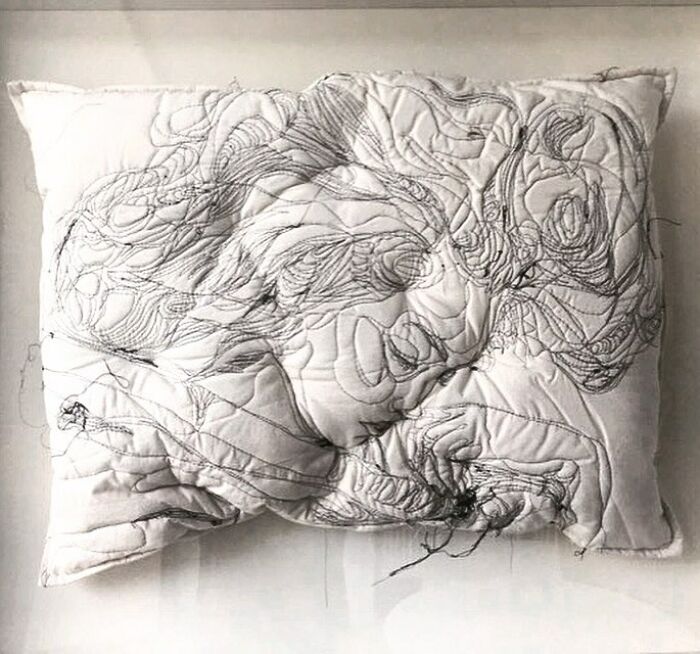 Embroidered pillow featuring a detailed stitched portrait of a sleeping woman, showcasing dreamy artistic embroidery.