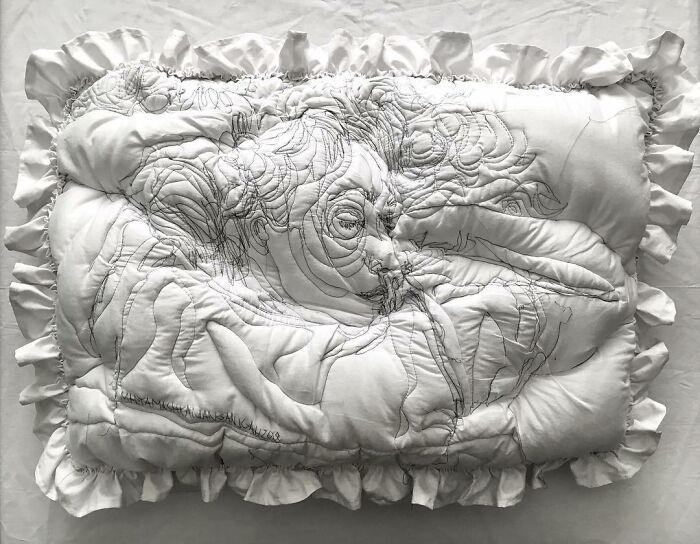 Embroidered pillow with detailed sketch of a sleeping woman on white fabric with ruffled edges, styled by Maryam Ashkanian.