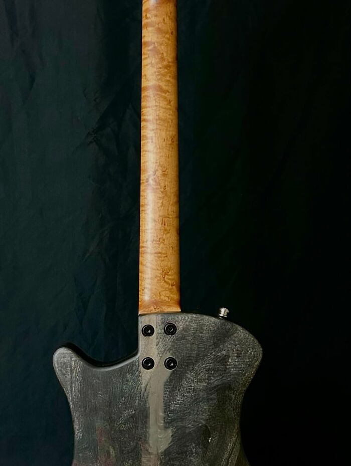 Electric guitar with a 3D molded body made from layered newspapers against a dark background.