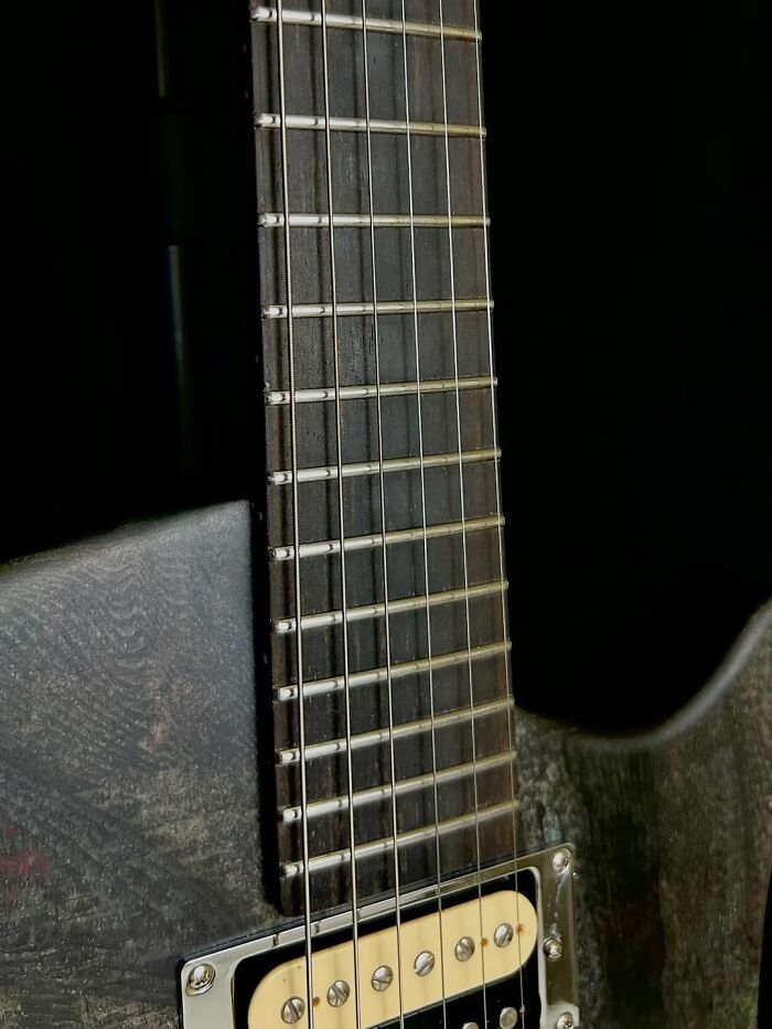 Close-up of a handmade guitar fretboard and strings created using a 3D mold from stacks of newspapers.