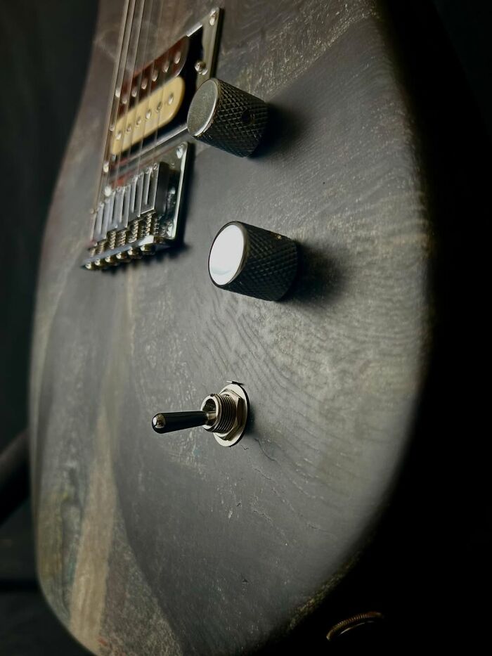 Close-up of a guitar made using a 3D mold and stacks of newspapers, showcasing its textured surface and controls.