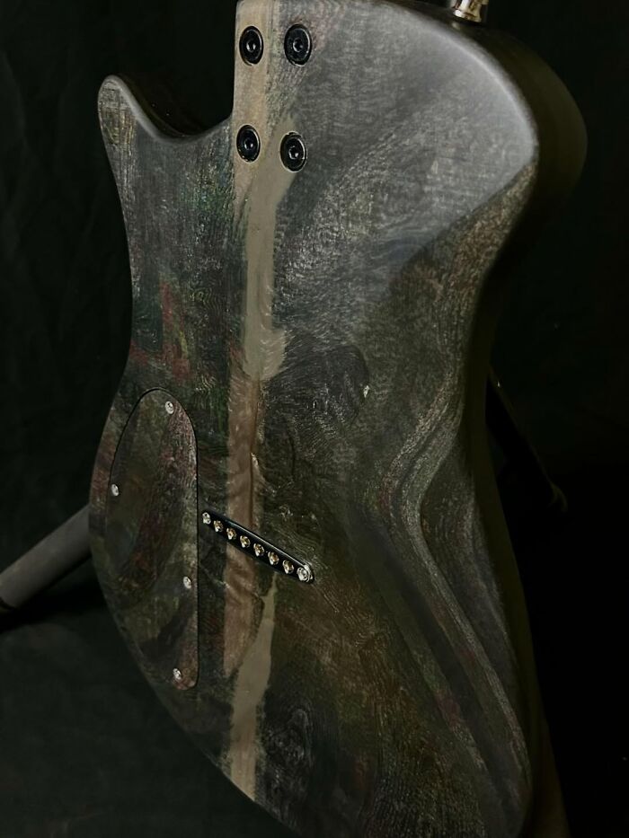 Electric guitar made using a 3D mold and stacks of newspapers, showcasing unique textured wood grain finish.