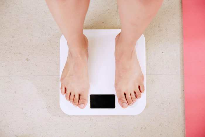 Person standing on a white scale, representing weight monitoring linked to scientists discovering Ozempic's healthier rival. Person standing on a white scale, representing weight monitoring linked to scientists discovering Ozempic's healthier rival.