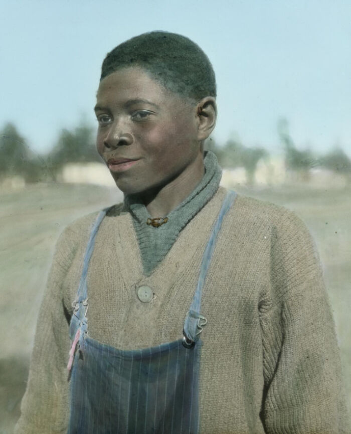 Young African American boy wearing sweater and overalls in a colorized photo depicting 1920s reality.