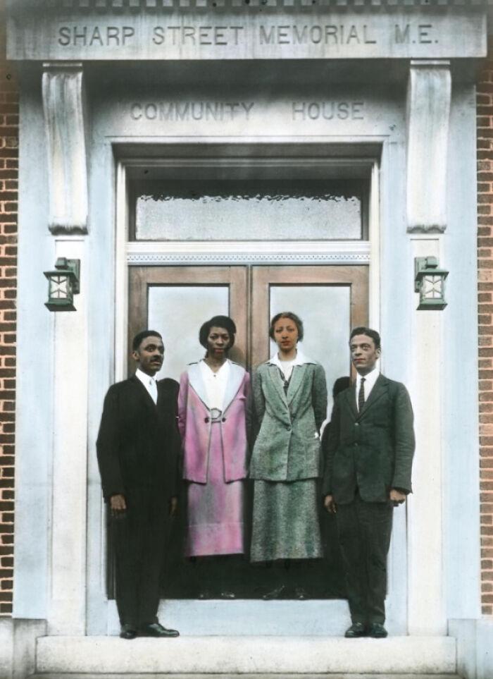Four African American adults in 1920s attire standing outside Sharp Street Memorial Community House, showing African American reality.