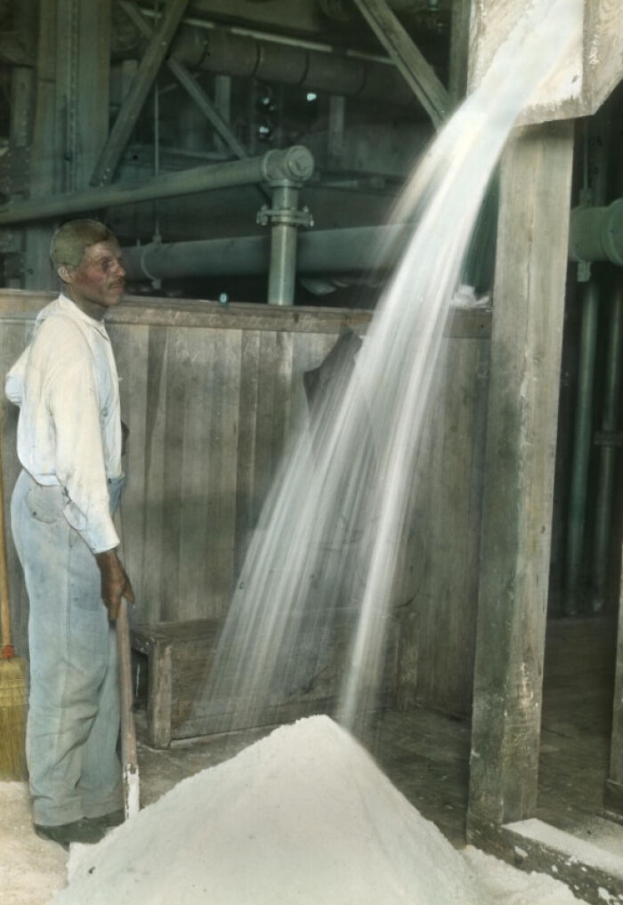 African American man working in a factory, pouring material onto a pile, showing 1920s industrial reality.