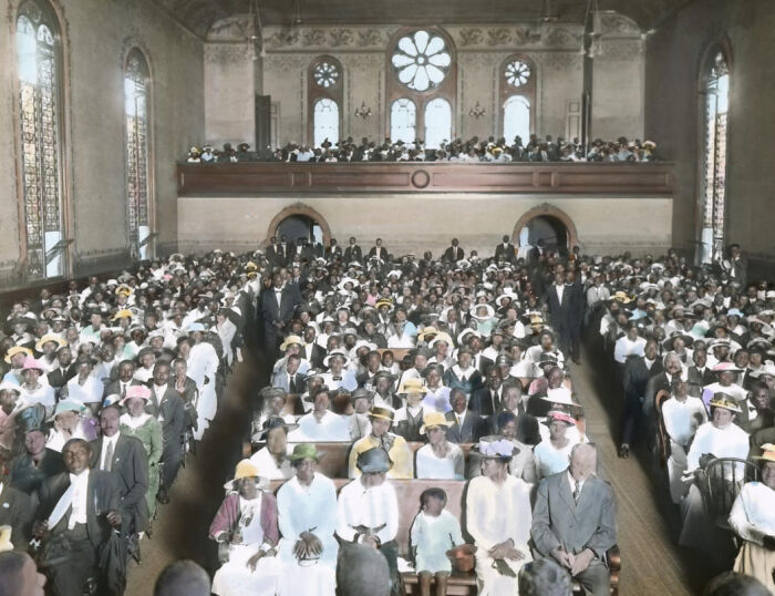 Large gathering of African Americans in church pews, showcasing the African American reality of the 1920s colorized photo.