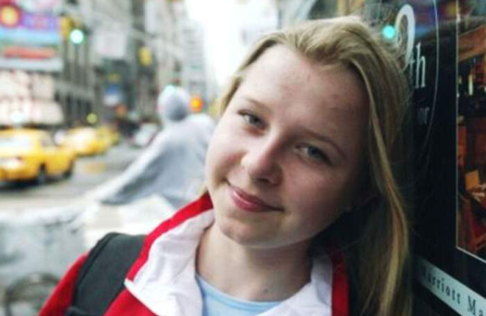 Young woman in a red jacket smiling on a busy city street, illustrating proof that superhumans walk among us