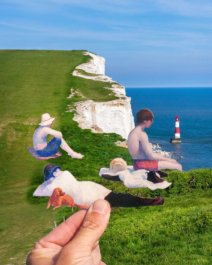 Hand holding paper cutouts of people relaxing on grass by the sea, artist travels the world creating scenes.