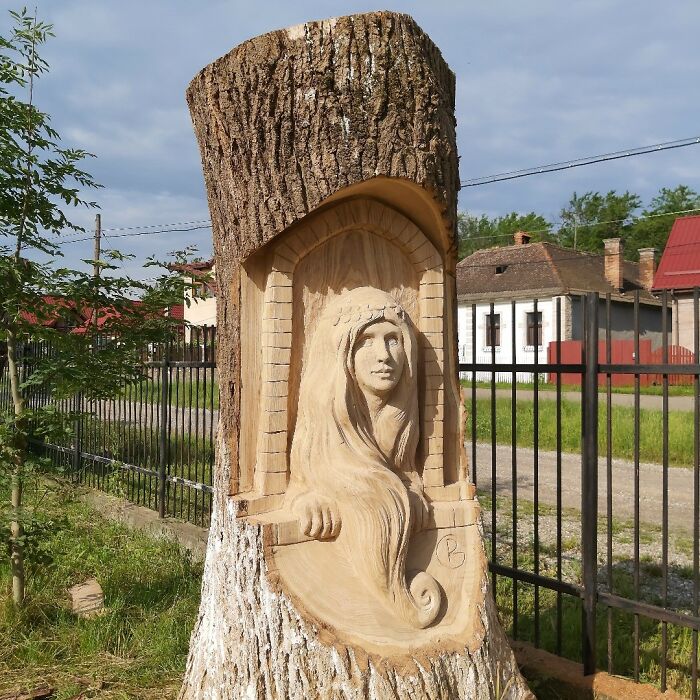 Chainsaw artist carving detailed female figure from a forgotten tree trunk, showcasing unique tree art outdoors.