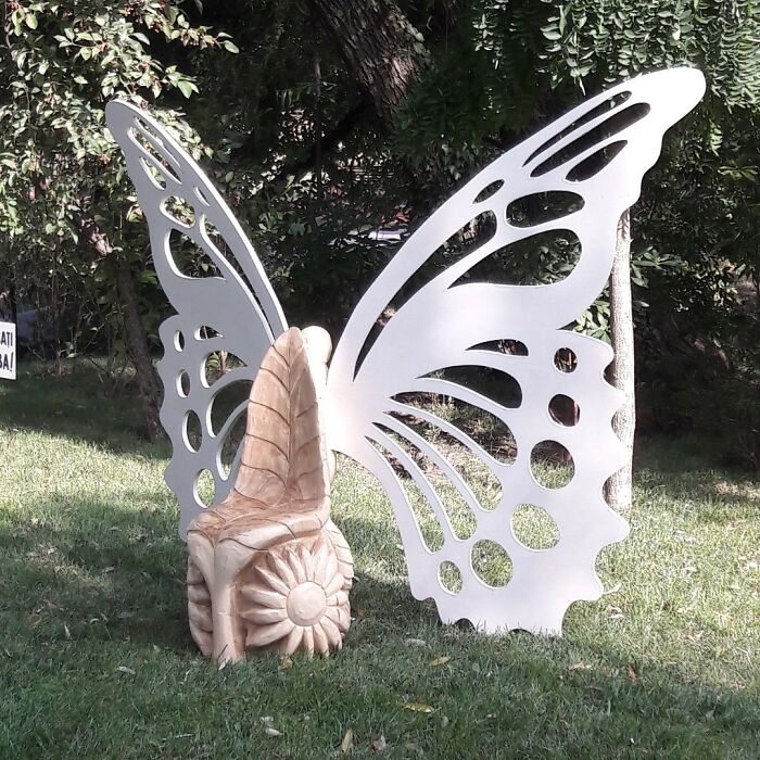 Wooden butterfly chair carved by chainsaw artist transforming forgotten trees into detailed outdoor art piece.