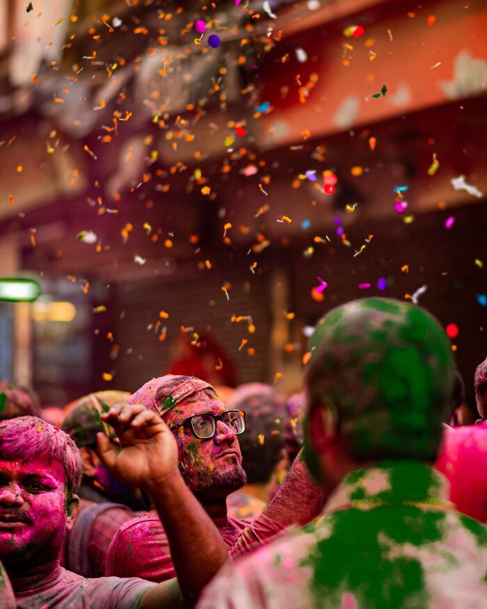 People covered in vibrant colors celebrate Holi festival in a lively street scene bursting with color and life in India.