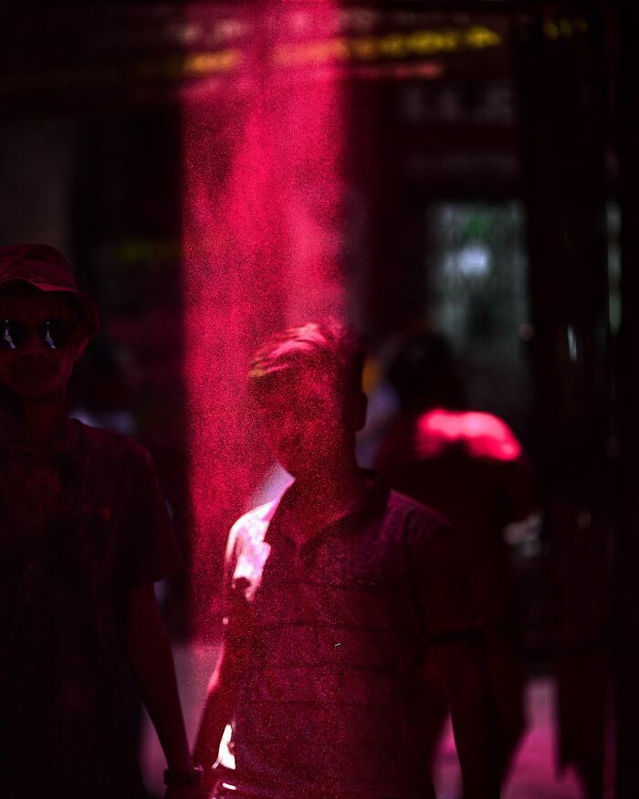 Two men surrounded by vibrant pink powder during a colorful celebration in India bursting with life and color.