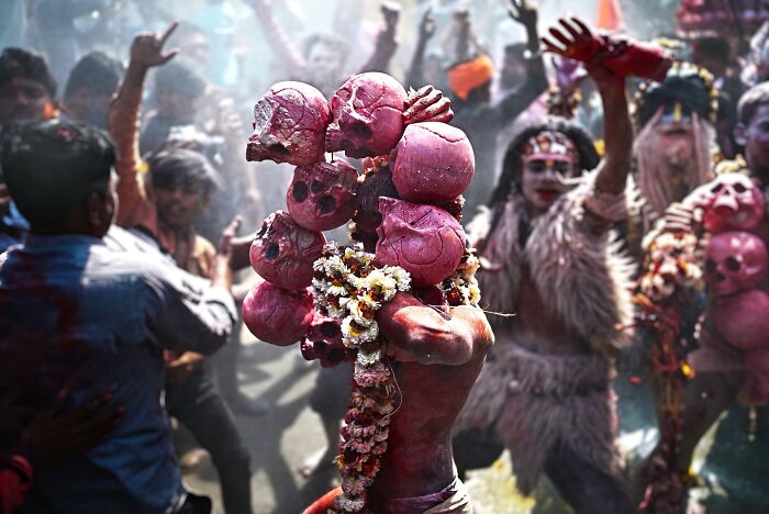 Colorful vibrant scene from an Indian festival with people adorned in traditional costumes and painted skull decorations.