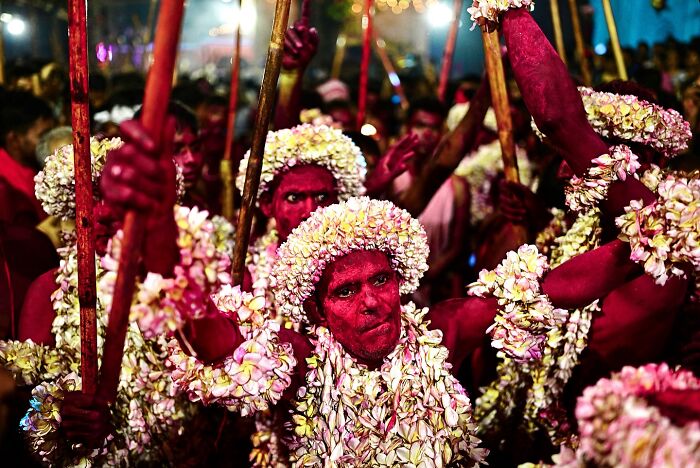 Men covered in bright red powder and adorned with white flower garlands celebrate during a vibrant festival in India bursting with color and life