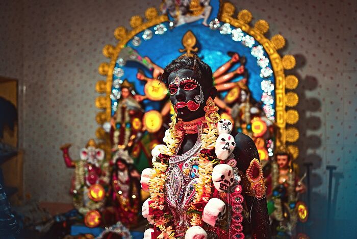 Colorful statue of a Hindu deity decorated with vibrant garlands and intricate face paint in India photography.