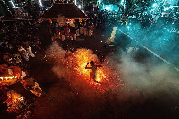 Man performing firewalking ritual surrounded by crowd at a vibrant cultural festival in India bursting with color and life