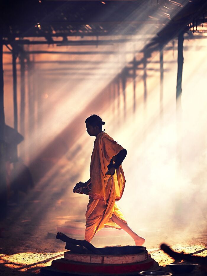 Silhouetted person in traditional attire walking through vibrant sunlit haze, showcasing vivid colors and life in India.