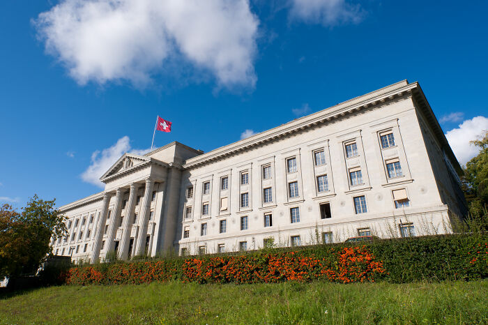 Historic government building with Swiss flag under a clear sky, symbolizing strong and unforgettable savage roasts.