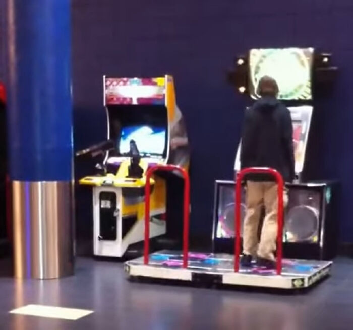 Person playing arcade dance video game near classic arcade machine in indoor entertainment area, highlighting videos with special context.