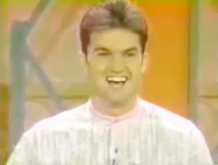 Smiling man in a vintage video frame with vibrant orange background, part of videos that gain meaning with context.