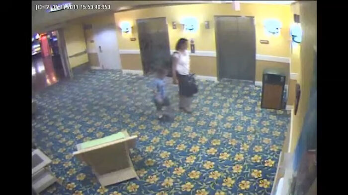 Security camera footage in a hotel hallway showing a woman and child walking near elevators, illustrating intriguing video context.