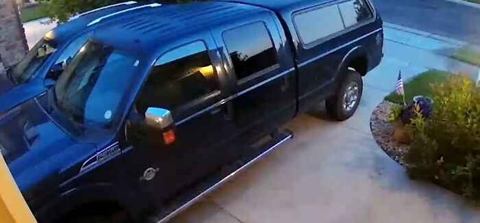 Black pickup truck parked in a residential driveway captured by a security camera for context in videos.