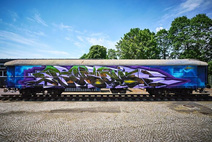 Graffiti mural on train car showcasing vibrant colors and blending realism and abstraction in urban street art style.