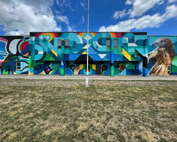 Colorful mural blending graffiti, realism, and abstraction with abstract shapes and a detailed hawk on an outdoor building wall.