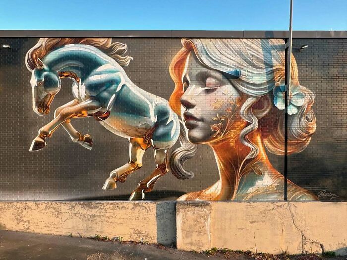 Mural blending graffiti, realism, and abstraction featuring a blue horse and a serene woman's face on a brick wall.