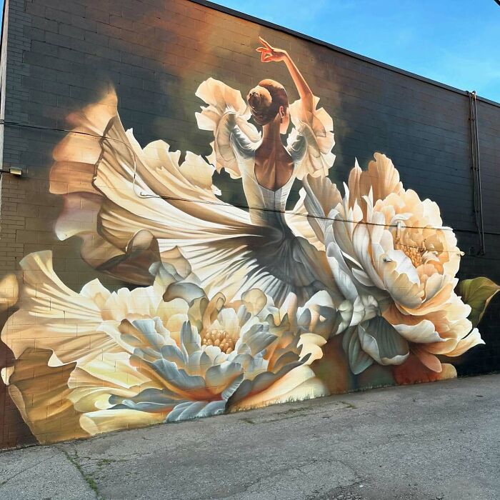 Mural by Alexander Vizsla Bacon depicting a dancer surrounded by large flowers blending graffiti and realism.