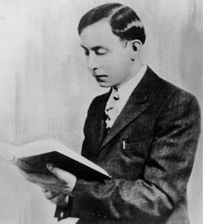 Black and white photo of a man in a suit reading a book, related to world’s greatest unsolved mysteries.
