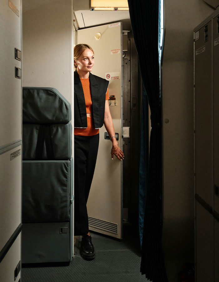 Woman standing near airplane lavatory door, illustrating extreme diarrhea incident causing emergency landing and flight cancellation. Woman standing near airplane lavatory door, illustrating extreme diarrhea incident causing emergency landing and flight cancellation.