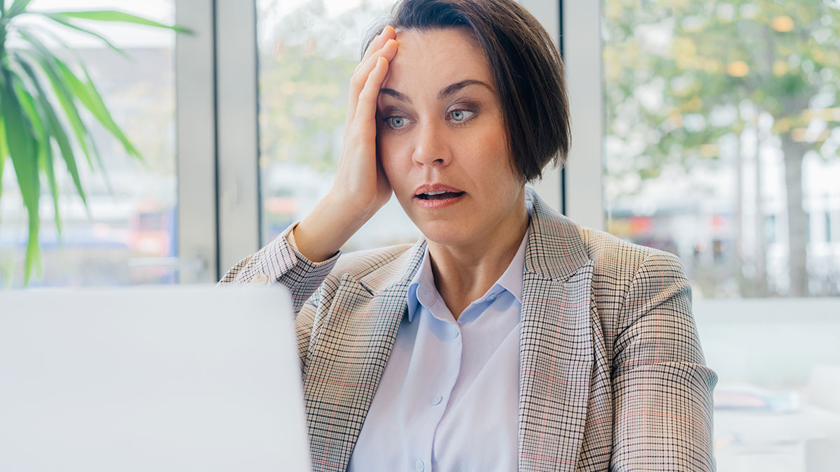 Woman looking surprised at laptop screen after getting an email about a second interview and a secret video file