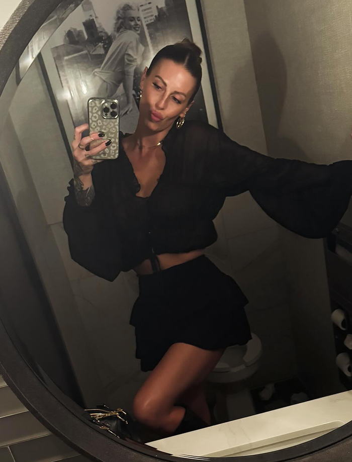 Mom with over 30 tattoos taking a mirror selfie wearing a black outfit, showing her tattooed arm and stylish look. Mom with over 30 tattoos taking a mirror selfie wearing a black outfit, showing her tattooed arm and stylish look.