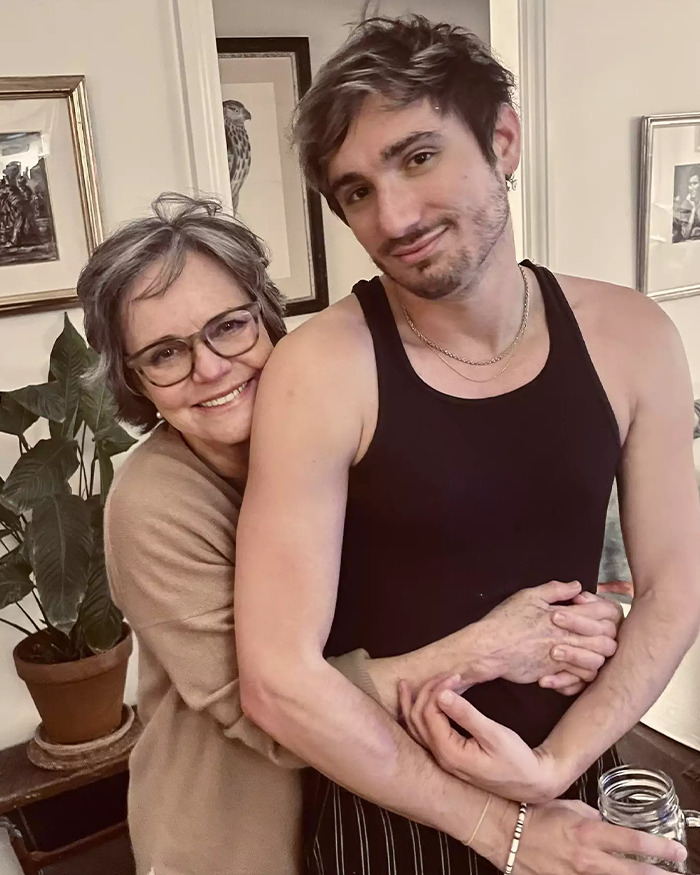 Middle-aged woman smiling and hugging young man in tank top, highlighting Andy Cohen viral roast of anti-LGBTQ activist. Middle-aged woman smiling and hugging young man in tank top, highlighting Andy Cohen viral roast of anti-LGBTQ activist.